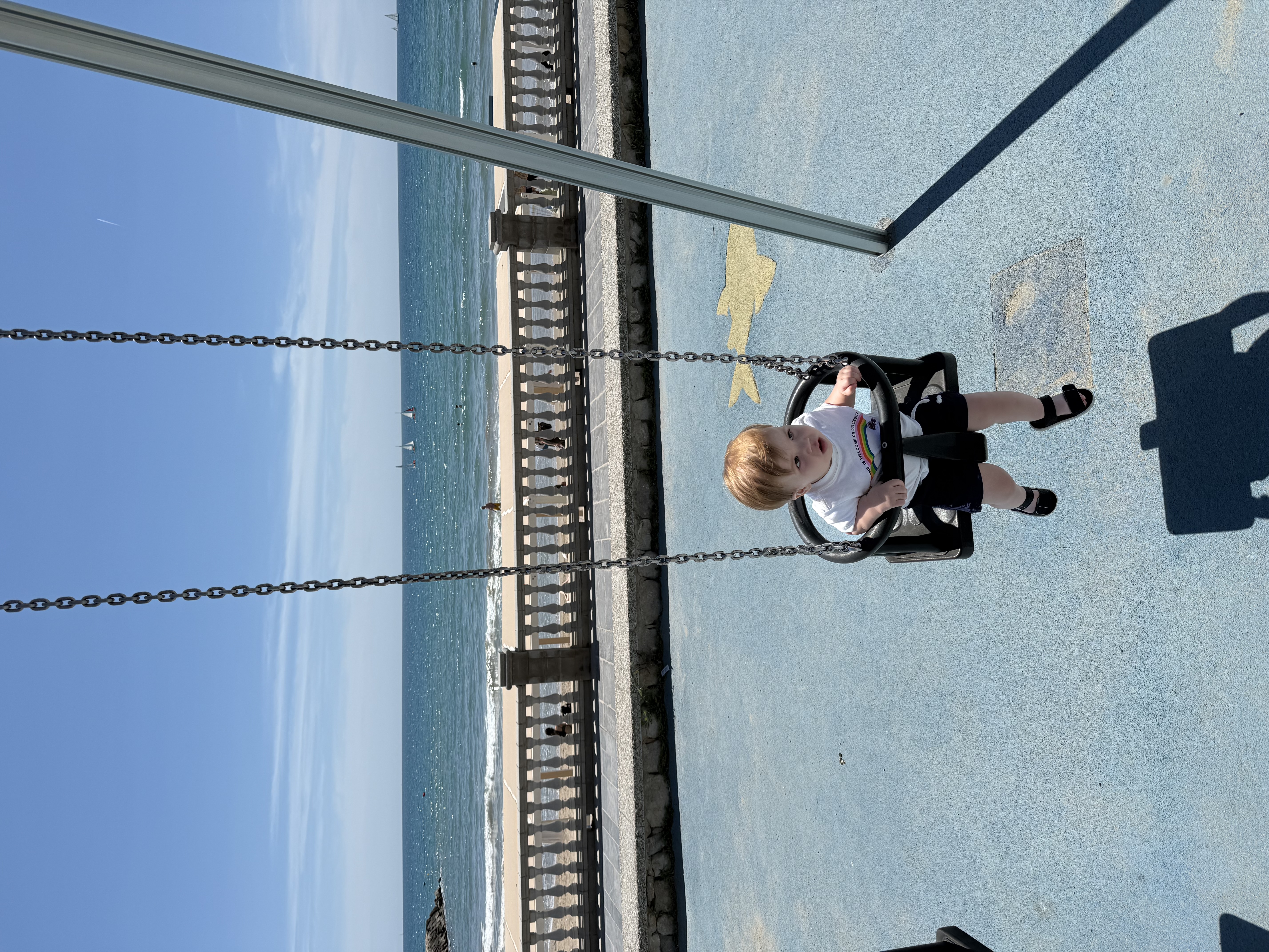 A toddler on a swingset overlooking the Mediterranean in Spain